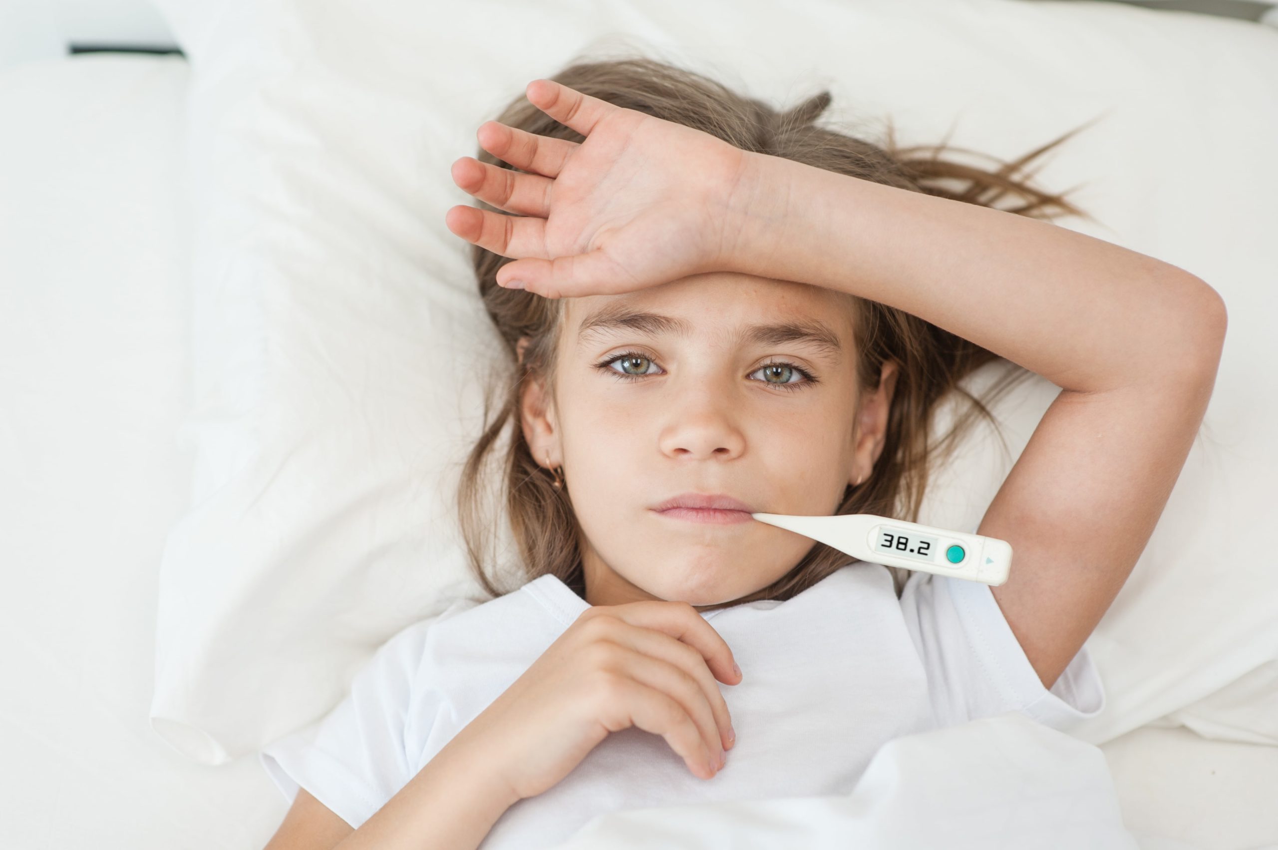 girl sick in bed with thermometer